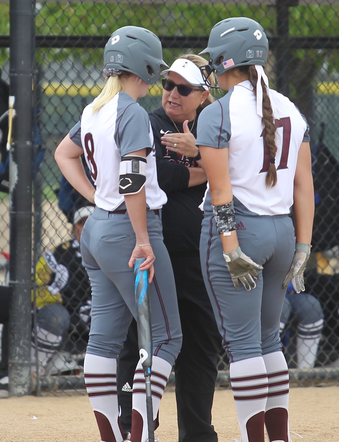 North Idaho College softball coach Don Don Williams talks strategy with Brianna Hecker, left, and Madi Mott.