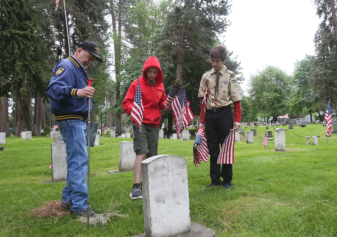 DEVIN WEEKS/Press 
Korean War veteran Bob Banta, left, assists Troop 911 Scouts Sean Hunt, 12, center, and Nolan Overland, 14, as they place a flag on a World War II veteran&#146;s grave Saturday morning in Forest Cemetery.