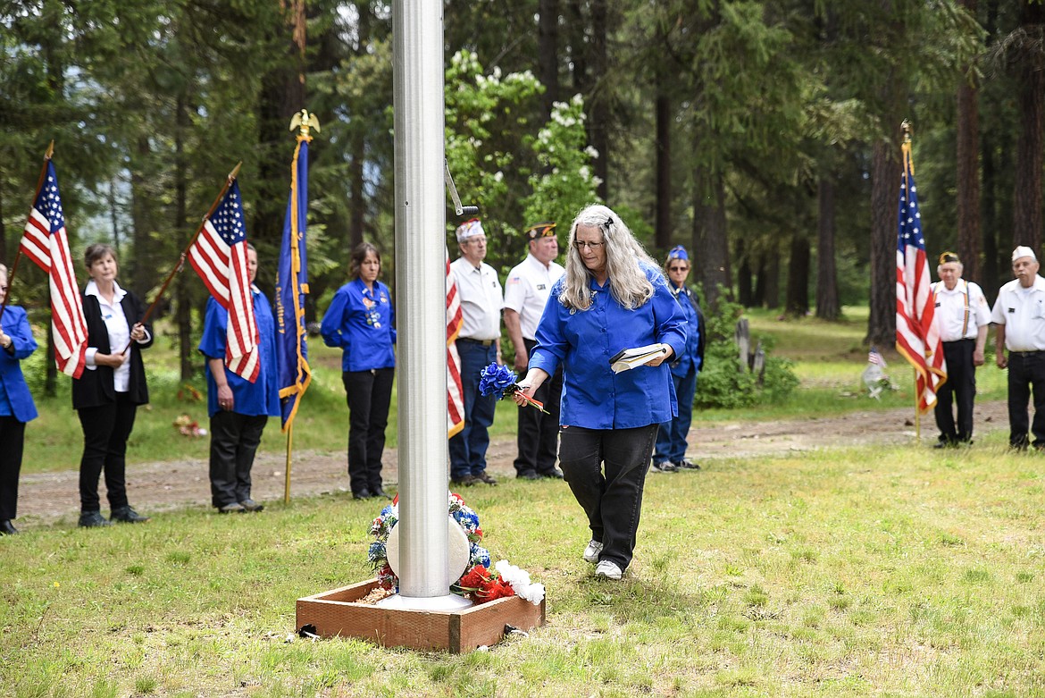 Francine Ninneman, Troy VFW Post 1548 Auxiliary president, approaches the flag pole to place blue flowers -- an emblem of eternity --  during the Memorial Day service at Troy Cemetery. (Ben Kibbey/The Western News)