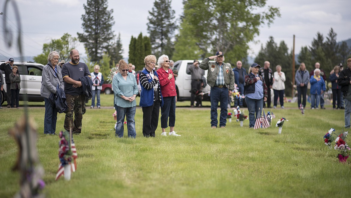 Memorial Day service attendees listen as taps is played, Monday at the Libby Cemetery. (Luke Hollister/The Western News)