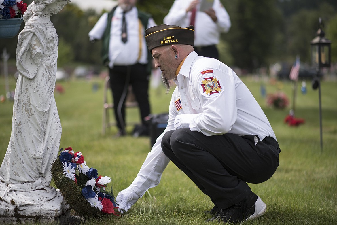 Libby Veterans of Foreign Wars member John Leary lays a flower down of sacrifices made by veterans during a Memorial Day service, Monday at the Libby Cemetery. (Luke Hollister/The Western News)