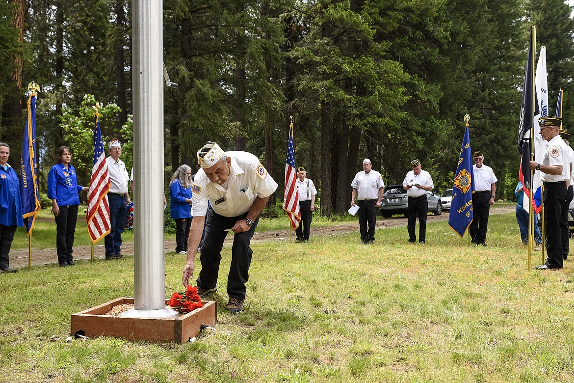 Post Commander Mark Olson, Troy VFW Post 1548 officer of the day, places red flowers &#147;In memory of the heroic dead who have fallen in defense of the United States of America,&#148; during the Memorial Day service at Troy Cemetery. (Ben Kibbey/The Western News)