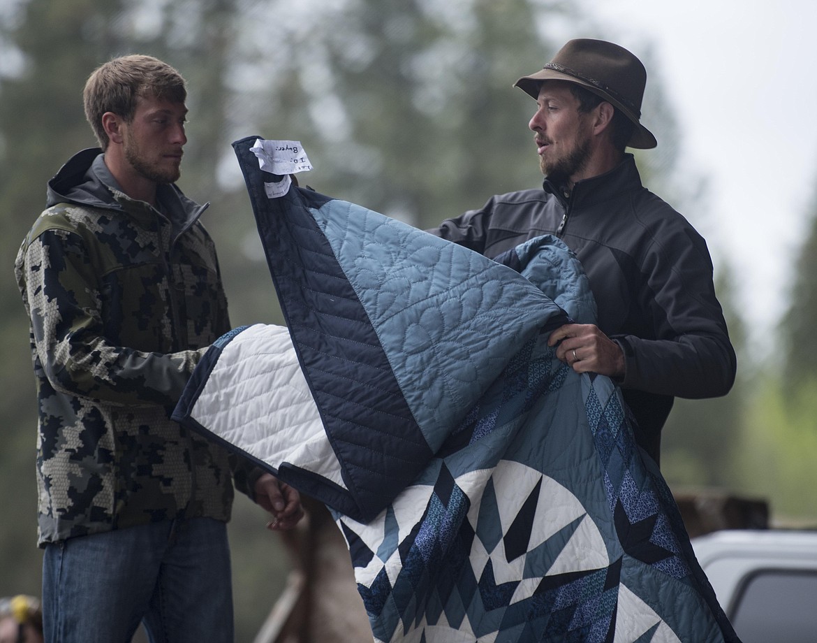 Organizers, William Hershberger, left, and Michael Yoder pull out a quilt to set on display during the annual amish Eagle Valley Community Auction, May 18. (Luke Hollister/The Western News)