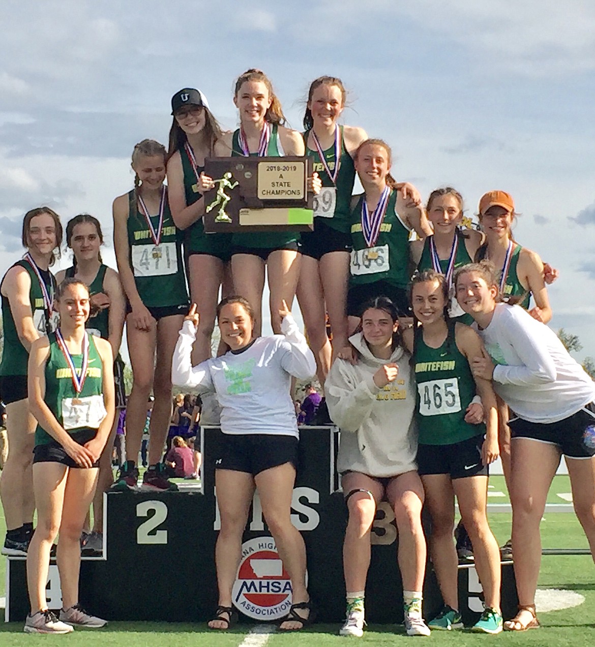 The Whitefish Bulldog girls track team on the podium with their Class A state championship plaque. (Photo courtesy Dana Grove)