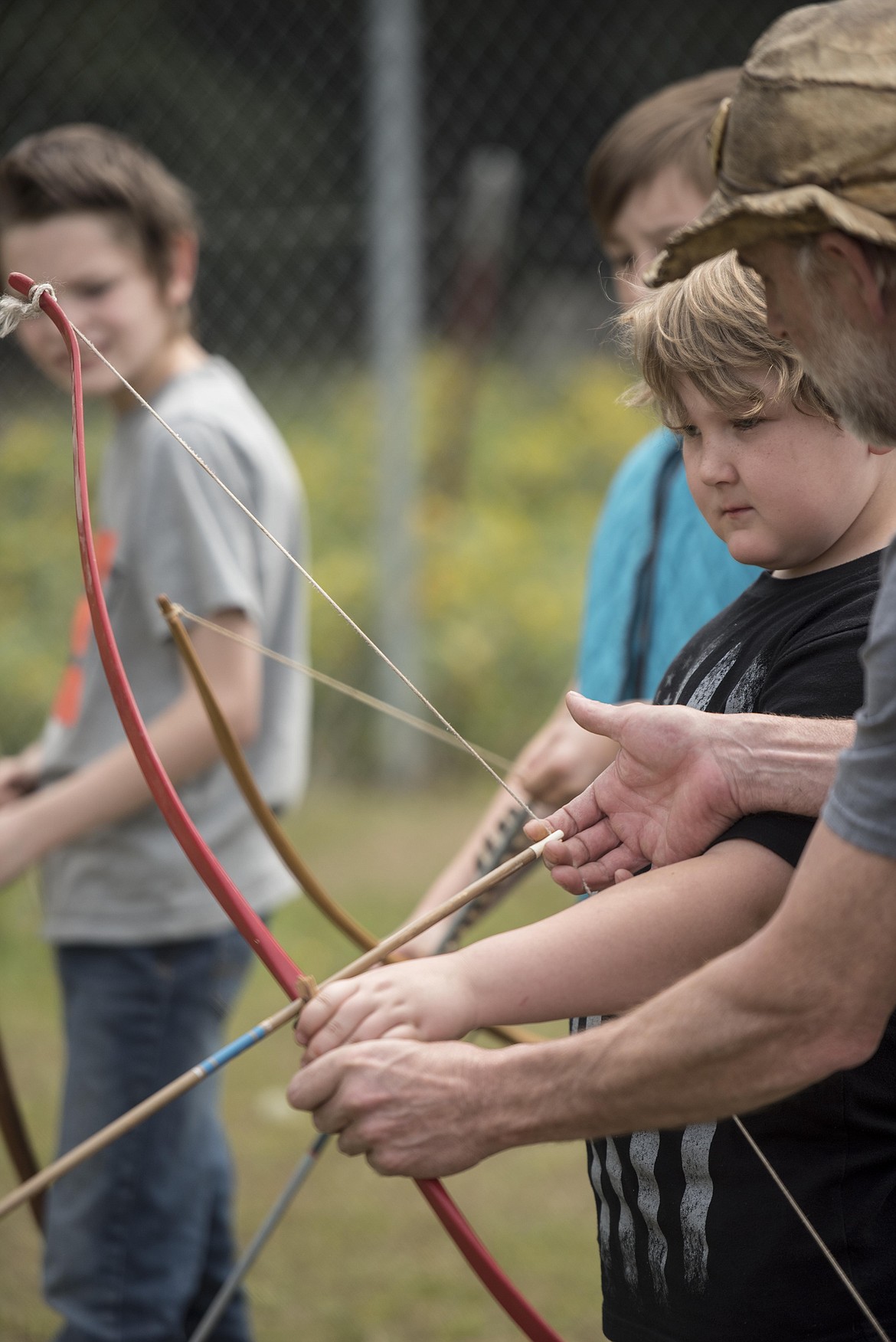 Aaron Roberts teaches Jarek Eide how to hold a bow and arrow, Wednesday at the McCormick School Rendezvous. (Luke Hollister/The Western News)