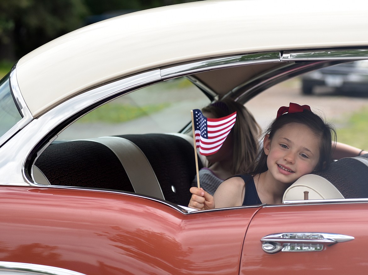 A youngster waves a flag from the backseat of a car in the Memorial Day parade. (Heidi Desch/Whitefish Pilot)