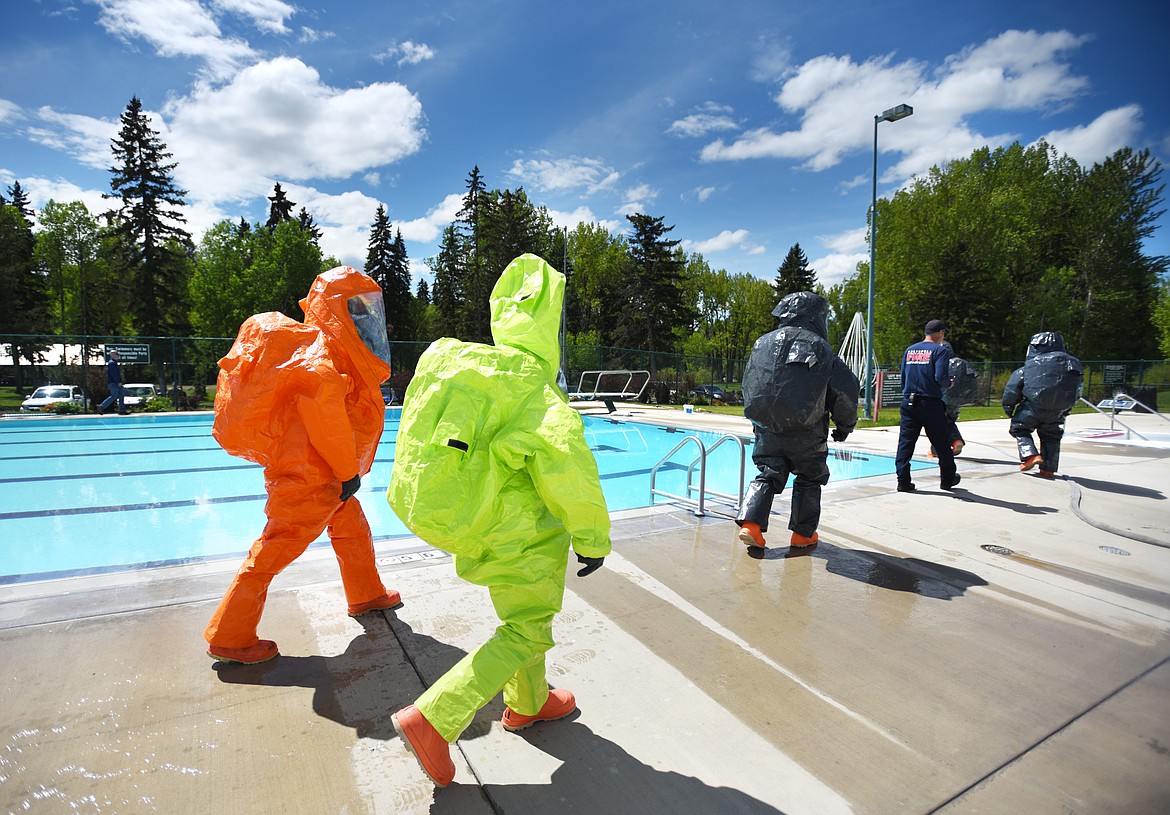 Kalispell Fire Department firefighters and members of the Montana National Guard 83rd Civil Support Team head to the Woodland Water Park pool to experiencing what they would have to deal with if they accidentally fell into water while working with a hazardous materials incident on Tuesday afternoon, May 21.(Brenda Ahearn/Daily Inter Lake)