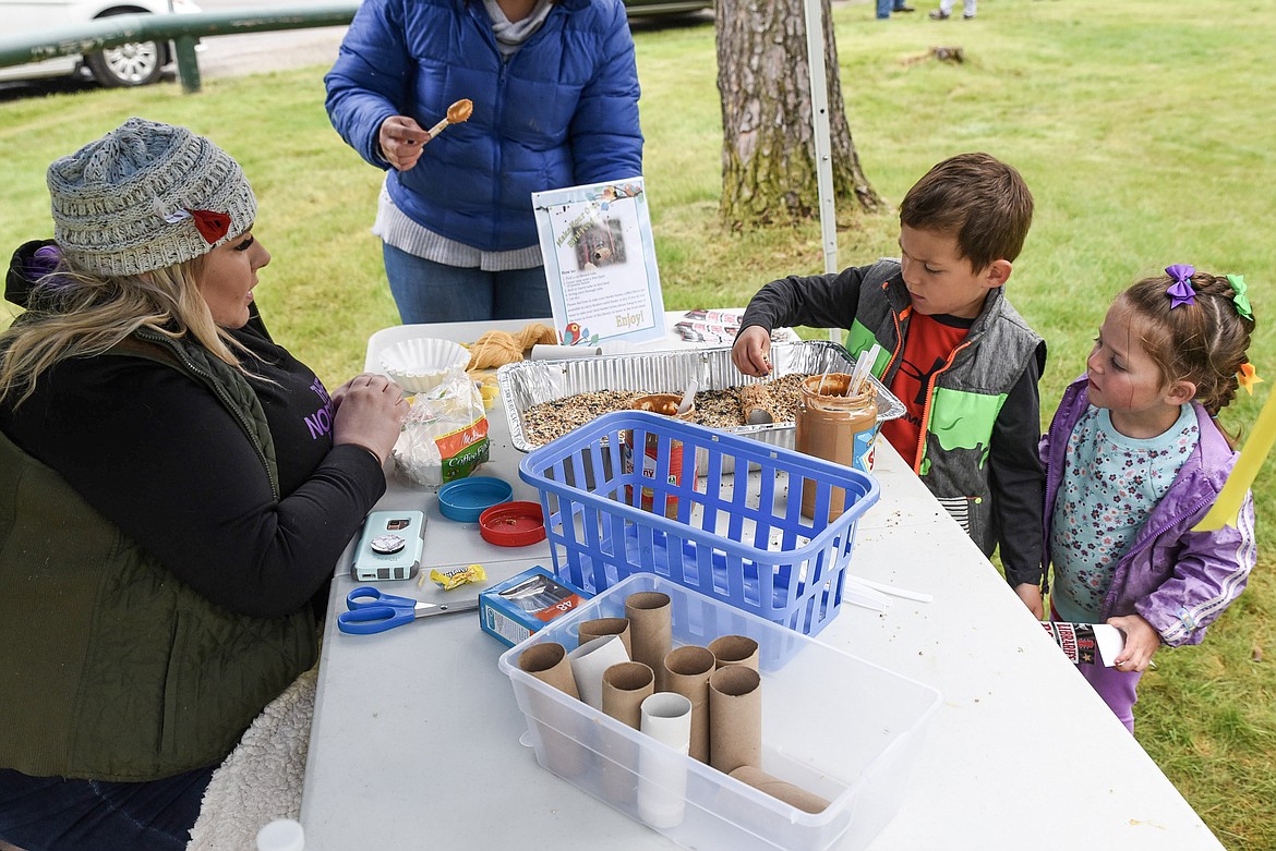 Dustina Deans with the Lincoln County Library talks with Caddis and Clover Karoglanian while Caddis works on a toilet paper roll bird feeder, at the Kootenai Kiwanis Family Fun Day at Fireman&#146;s Park in Libby last Saturday. (Ben Kibbey/The Western News)