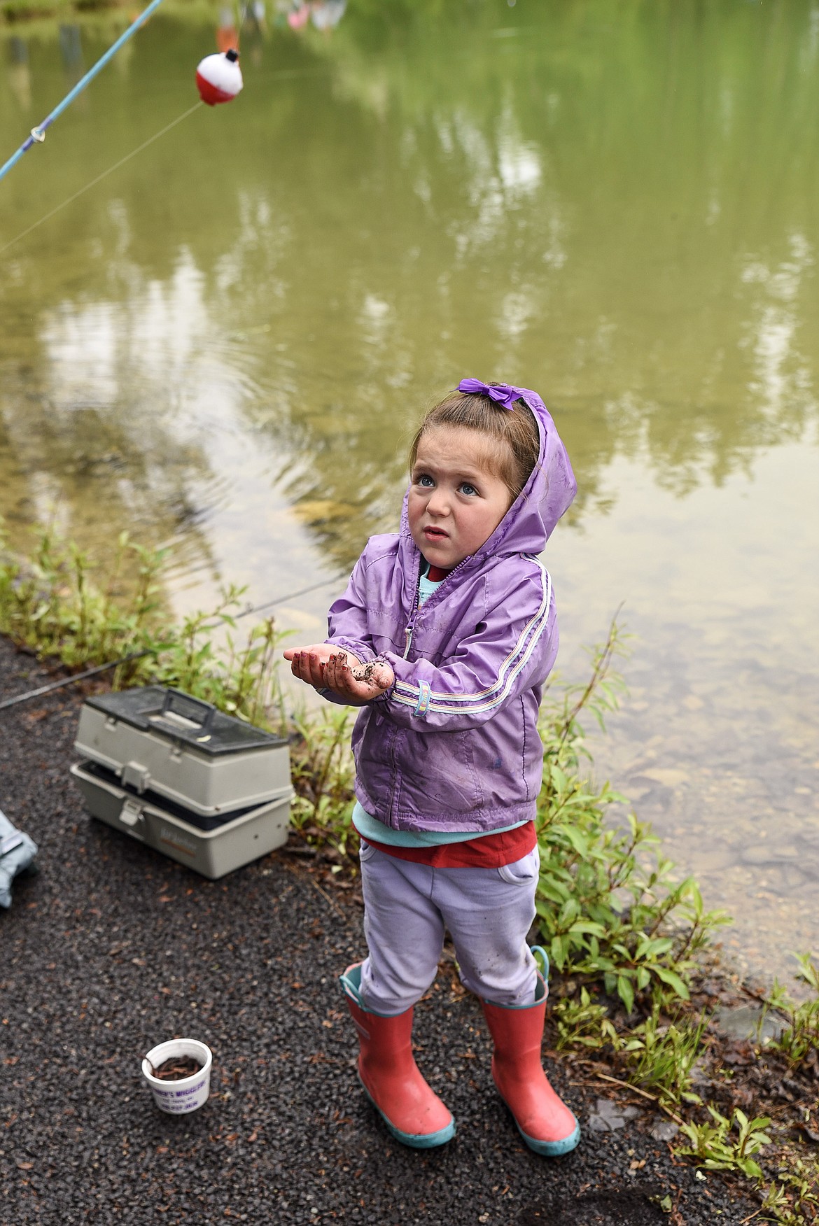 Bottom: Clover Karoglanian holds up a worm before getting to the fishing at the Lil&#146; Anglers Fishing Day at the Mill Pond on Saturday (Ben Kibbey/The Western News)