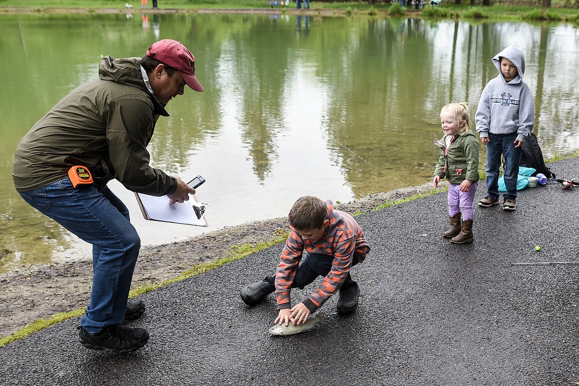 Top: Levi Nick chases down his catch as event judge Craig Barringer with Rotary gets ready for a picture and Page and Braiden Nick watch, at the Lil&#146; Anglers Fishing Day at the Mill Pond on Saturday (Ben Kibbey/The Western News)