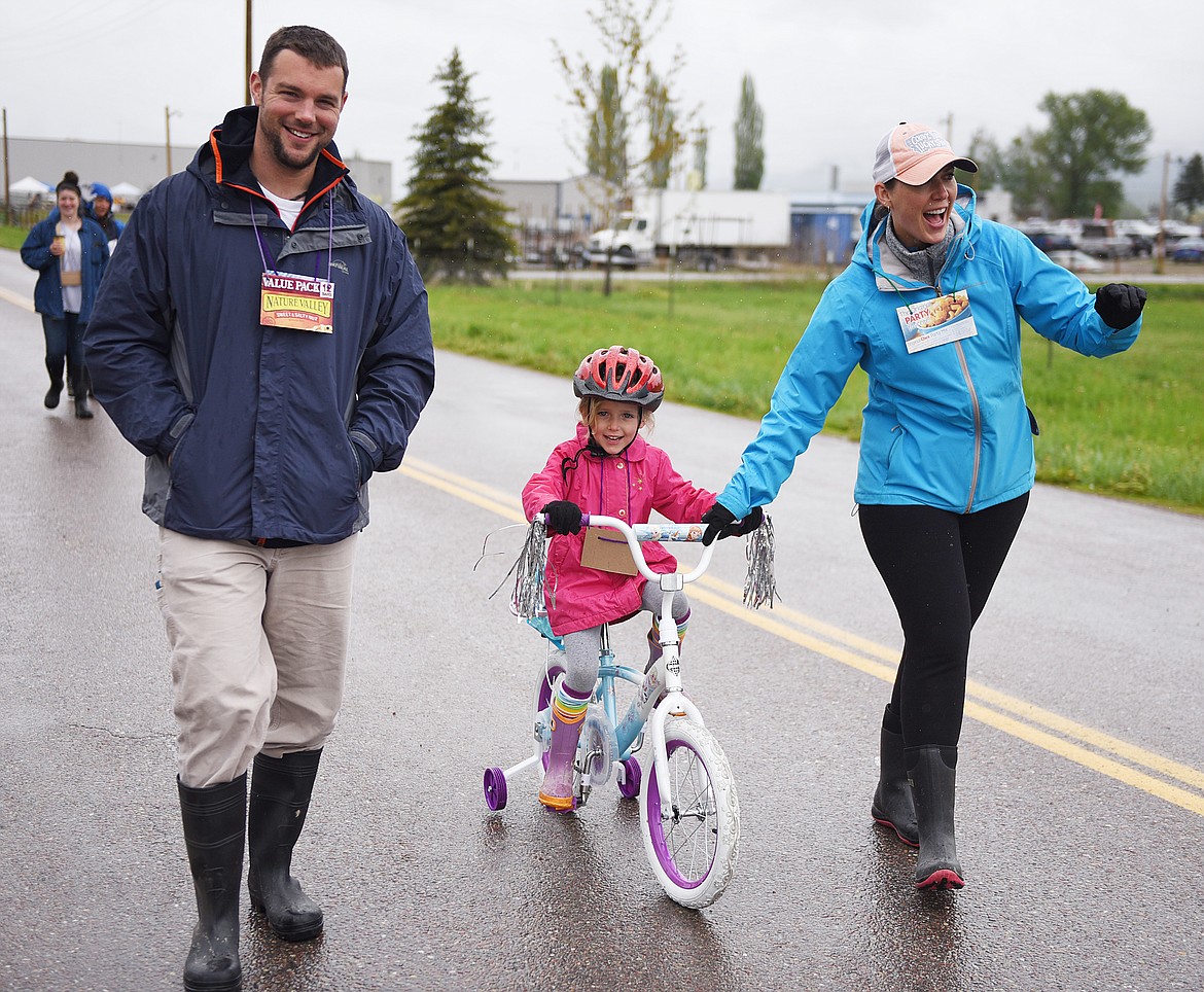 WHITNEY CANTLAN assists her 5-year-old daughter Elise at the Pedal to Plate while dad David watches.