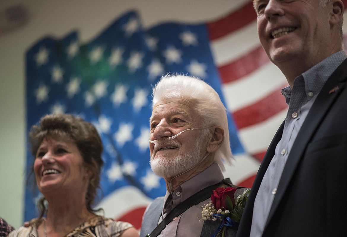 Veteran John Alex, middle, stands with U.S. Rep. Greg Gianforte of Montana, right, as he is applauded after being awarded the Montana Congressional Veteran Commendation, Friday at the Libby Veterans of Foreign Wars Post 1548. (Luke Hollister/The Western News)