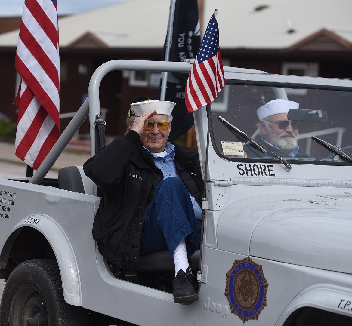 JIM SIVELLE, a U.S. Navy veteran who served during World War II, salutes while riding with comrade Roger Rasmussen during the Memorial Day parade in Ronan. Sivelle said he was in Tokyo Bay aboard the USS Detroit during the signing of surrender by the Japanese on Sept. 2, 1945. Rasmussen, a Navy veteran, served aboard the destroyer USS Everett F. Larson in the Vietnam War.