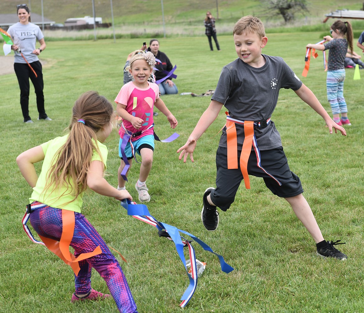 SECOND GRADER Alex Farrar attempts to stop Cooper Spur while Zoey Halden approaches during a flag tag game at the Plains Elementary Track and Field Day on May 21. 
(Carolyn Hidy photos/Clark Fork Valley Press)