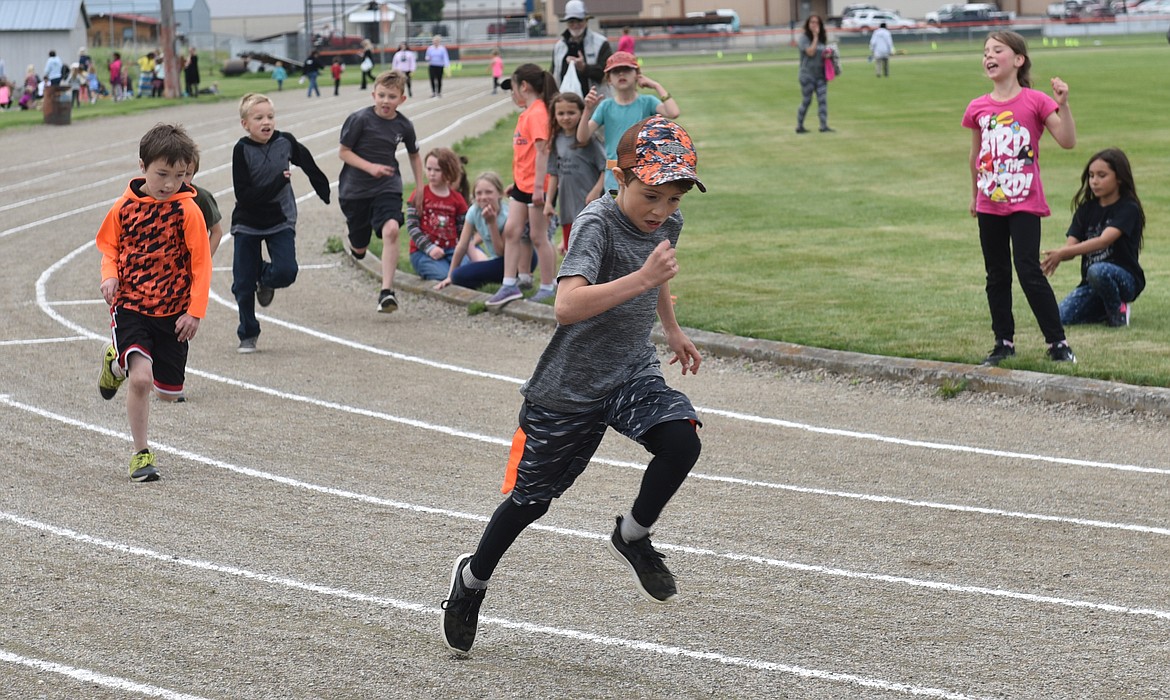 SECOND GRADERS Jackson Revier (lead runner) followed by Bryan Lakko, Cordell Foley and Alex Farrar are being cheered on by Emery Josephson (pink shirt) during Track and Field Day.