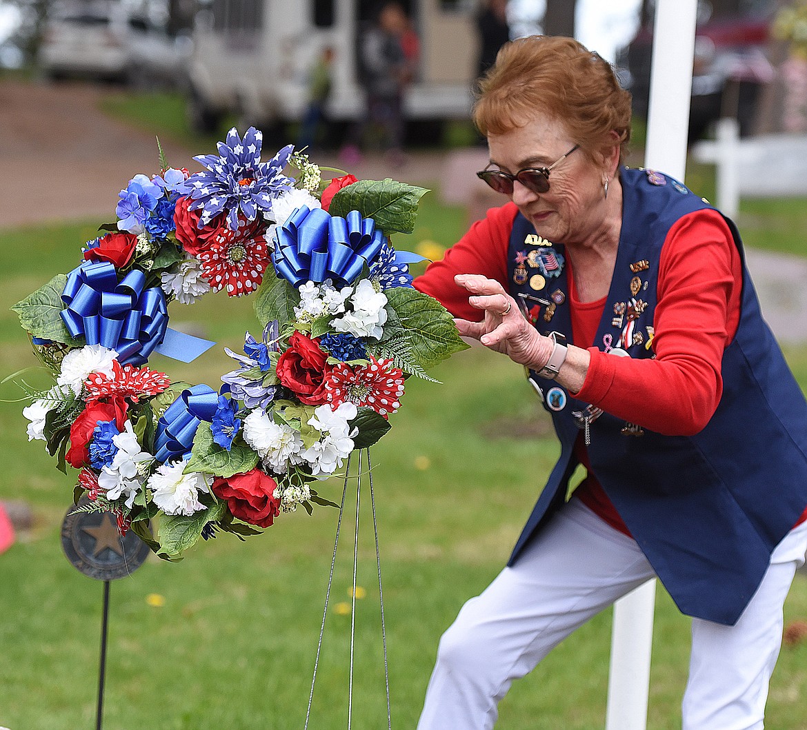 JESSE MERWIN, a member of the VFW Auxiliary in Ronan, places the traditional Memorial Day wreath near the entrance to the Ronan Cemetery on Monday afternoon.