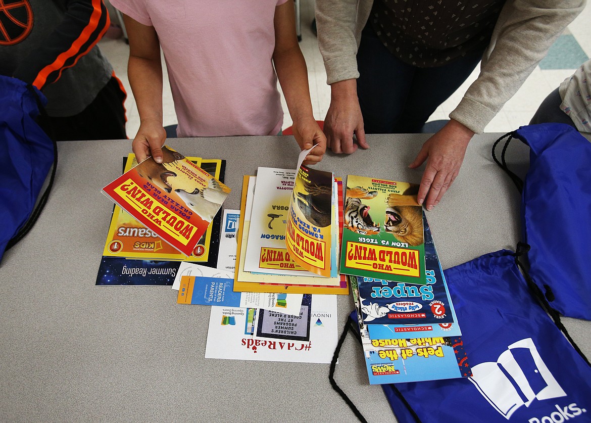 A first-grade student glances through books during Opening Books, Opening Doors distribution day Wednesday at Dalton Elementary School. (LOREN BENOIT/Press)