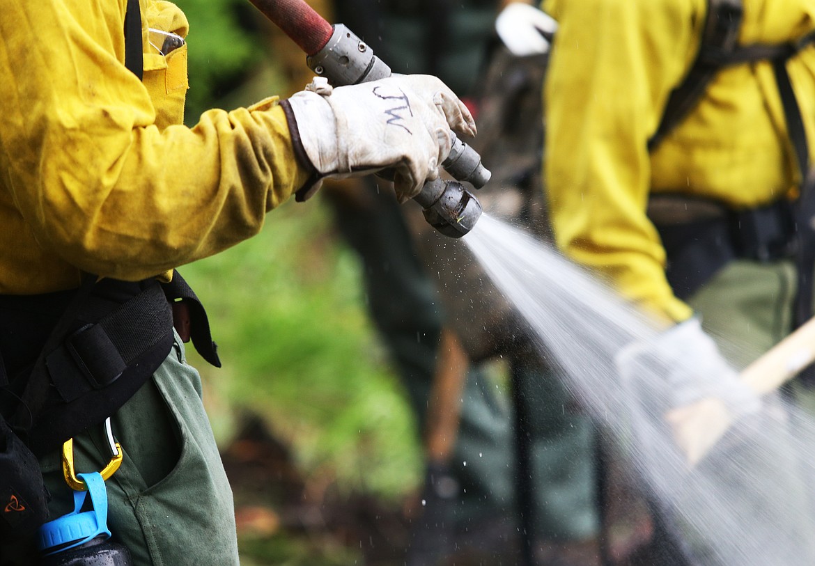 A wildland firefighter sprays water on a control burn fire during a training exercise Thursday south of Coeur d'Alene up Cougar Gulch. (LOREN BENOIT/Press)