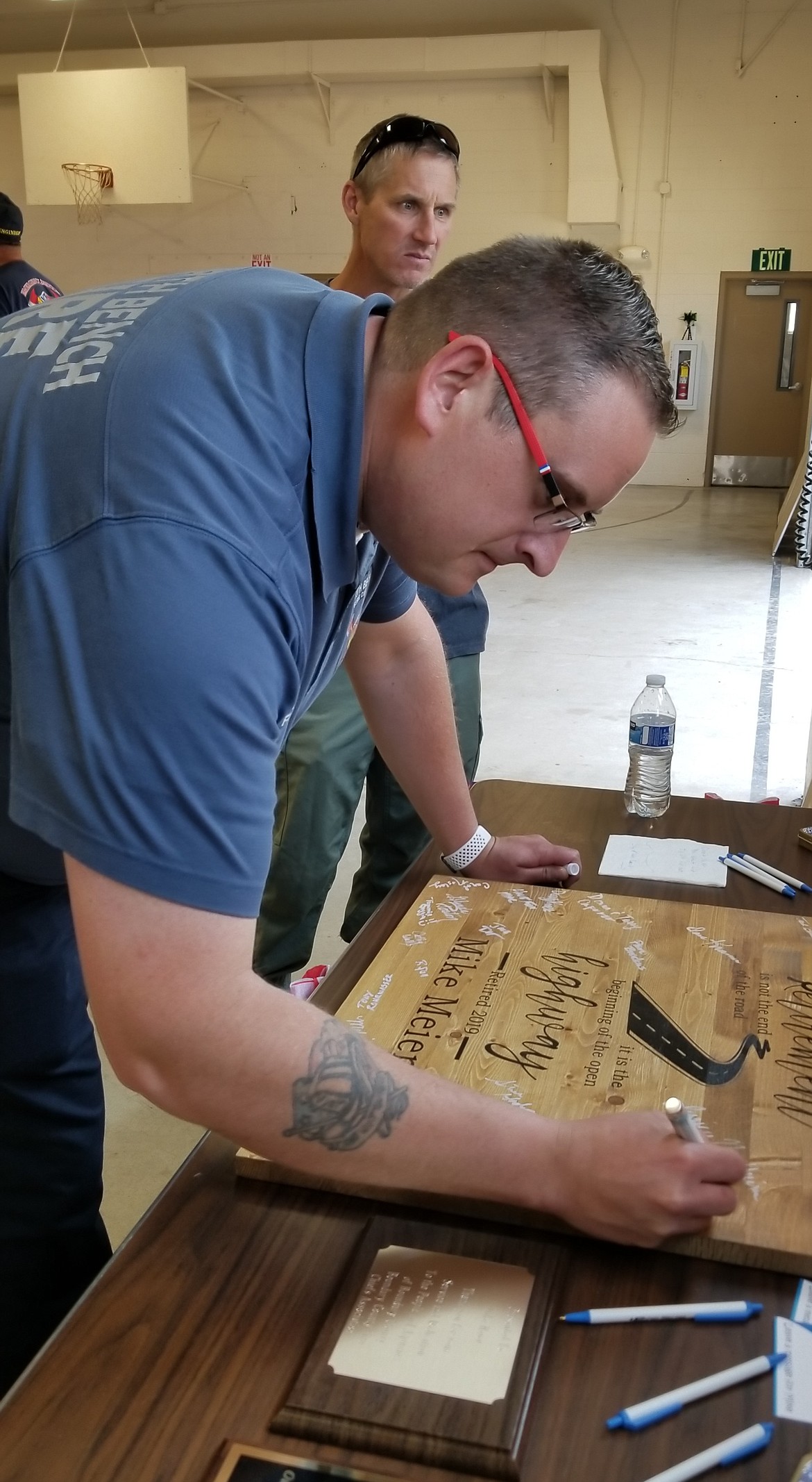 Photo by MANDI BATEMAN
North Bench Fire Chief Gus Jackson signs Mike Meier&#146;s retirement plaque.