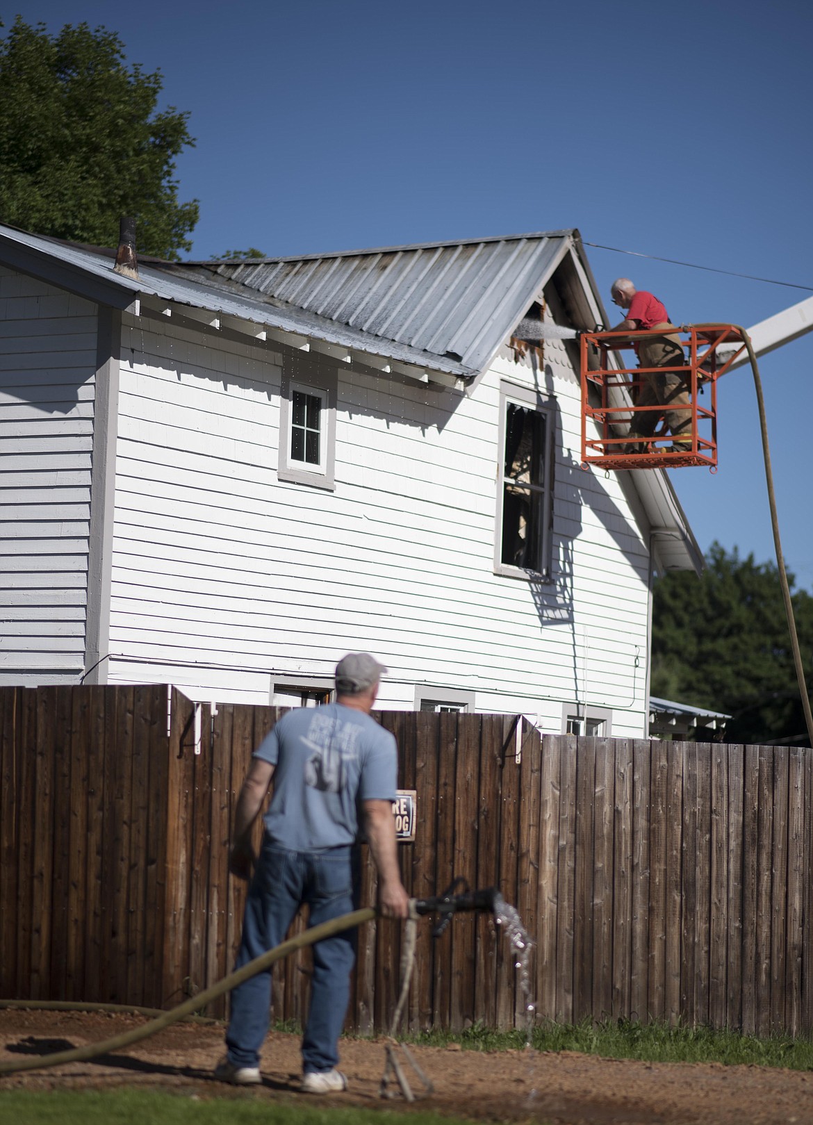 Troy Volunteer Fire Department Fire Marshal Gene Rogers, top, puts out the last of house fire in Troy, early Tuesday morning along Riverside Avenue. (Luke Hollister/The Western News)