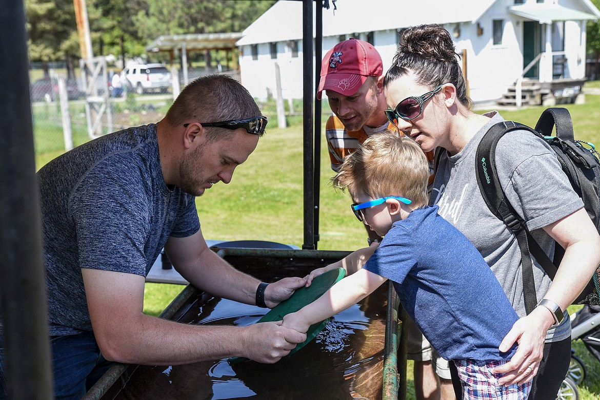 Zane Officer shows Owen Teisberg how to pan for gold as Justin and Kerri Teisberg look on, at the Heritage Museum&#146;s Opening Day in Libby Saturday. (Ben Kibbey/The Western News)