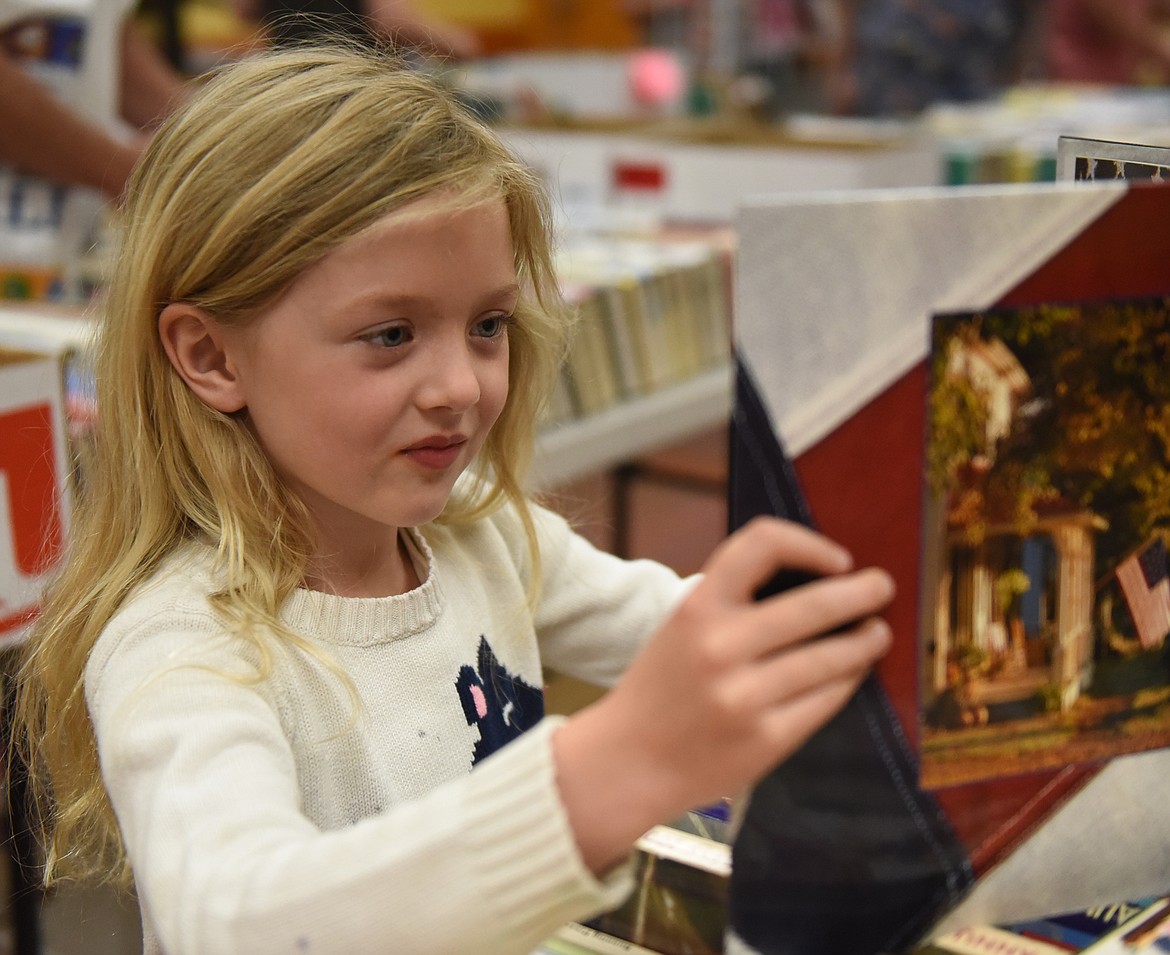 ABOVE, LUCY LOVE looks through a book, &#147;The American Flag.&#148; Left, Lynn Johnson bags books to take home. Below, Paula Aznoe checks Marlys Healy out during the sale.