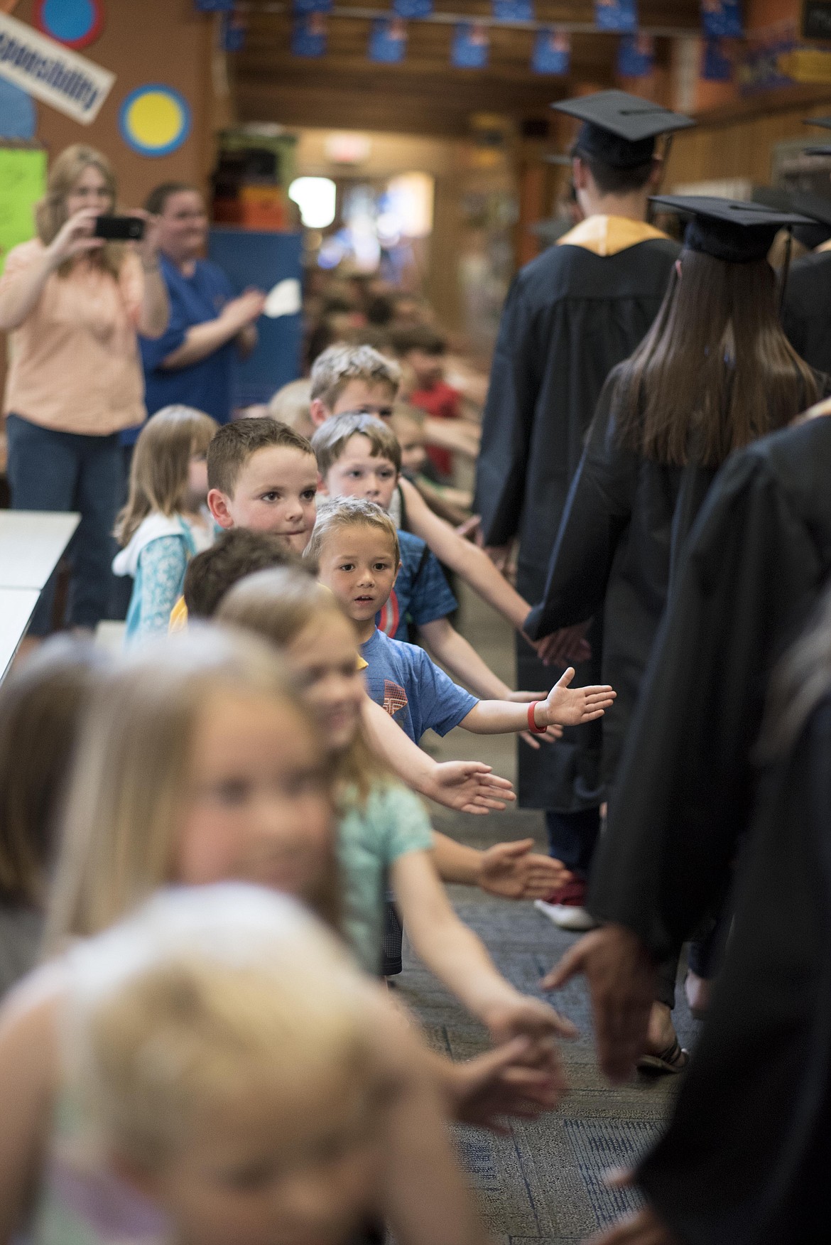 Rows of elementary schoolers line up, cheering Libby's graduating senior to the sound of Pomp and Circumstance played through the Libby Elementary School's intercom, Friday. (Luke Hollister/The Western News)