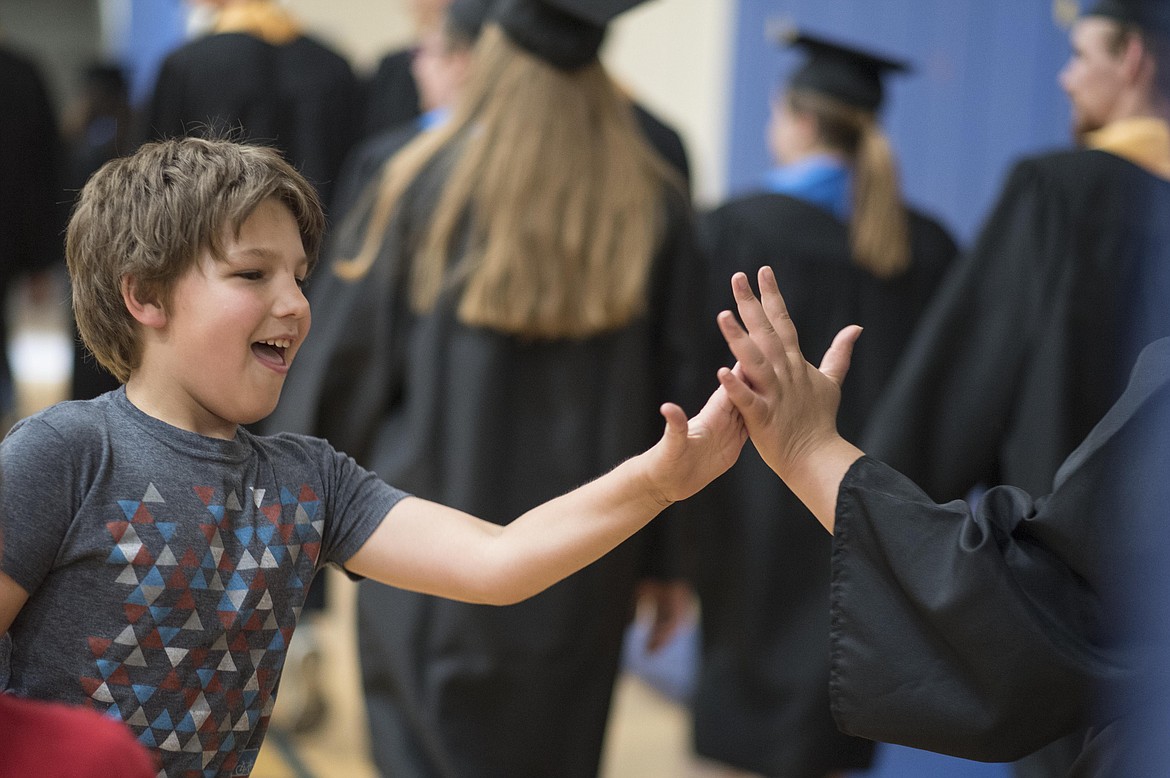 A student gives high fives to Libby's graduating seniors as they walk through the Libby Elementary School gym, Friday. (Luke Hollister/The Western News)