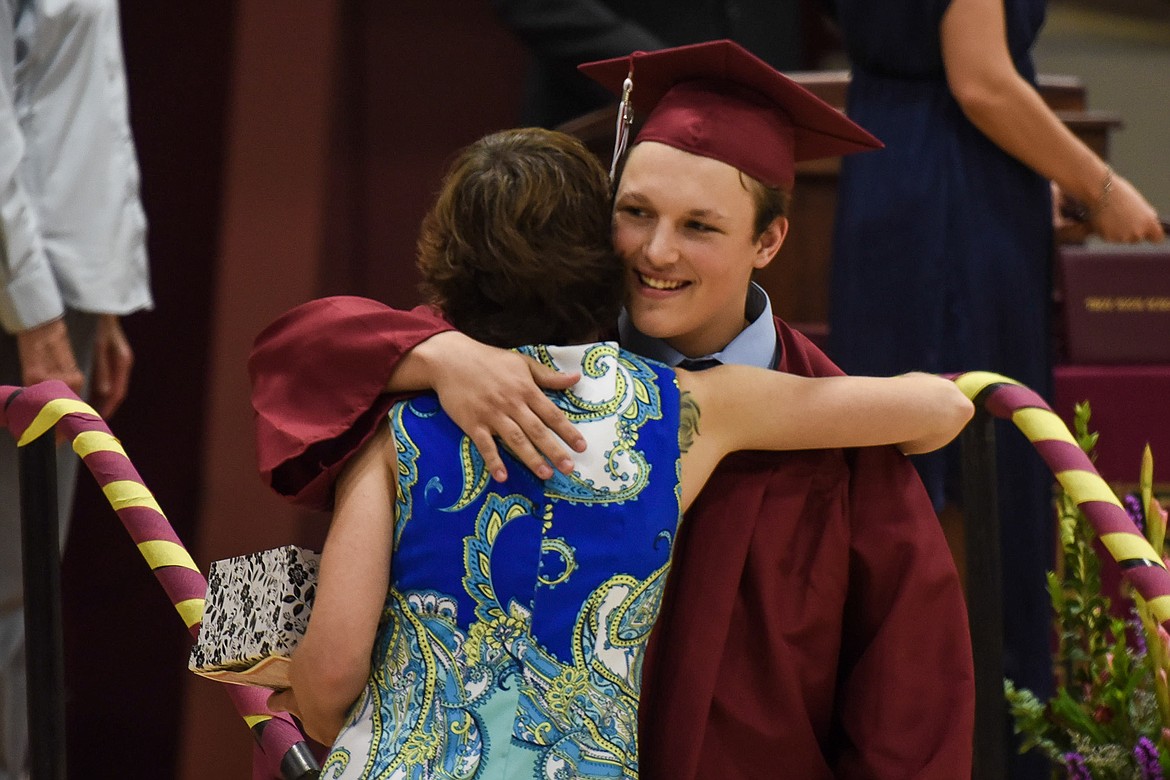 Logan Milde pauses to hug honorary speaker and Troy Spanish teacher Tabitha Maust after receiving his diploma, Saturday at the Troy High School graduation at the Troy Activity Center. (Ben Kibbey/The Western News)