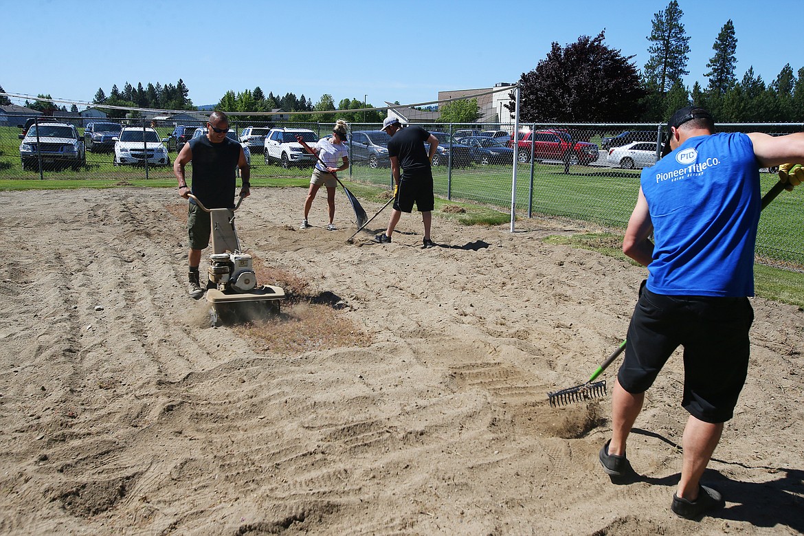 From left, Windermere Realtor Jeff Andersen, Managing Post Falls Windermere Broker Jennifer Smock, Realtor Ryan Keller and Derrin Halliday with Pioneer Title Company remove weeds and rake the volleyball court at Children's Village during Windermere's Community Service Day on Friday. (LOREN BENOIT/Press)