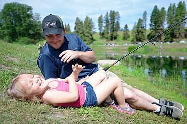 Derrick Downing, of Columbia Falls, tickles his daughter Denolly, 4, as they wait for a fish to bite during the Robin Street Memorial Family Fishing Day hosted by Montana Fish, Wildlife &amp; Parks at Pine Grove Pond in Kalispell on Saturday. (Casey Kreider/Daily Inter Lake)