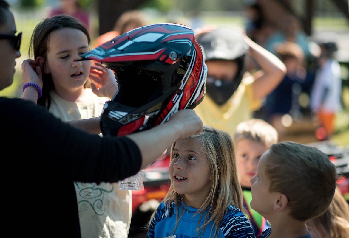 Mya Sloan, middle, tries out a new helmet during a 4-wheeler training workshop for children at J. Neils Memorial Park, Tuesday. (Luke Hollister/The Western News)