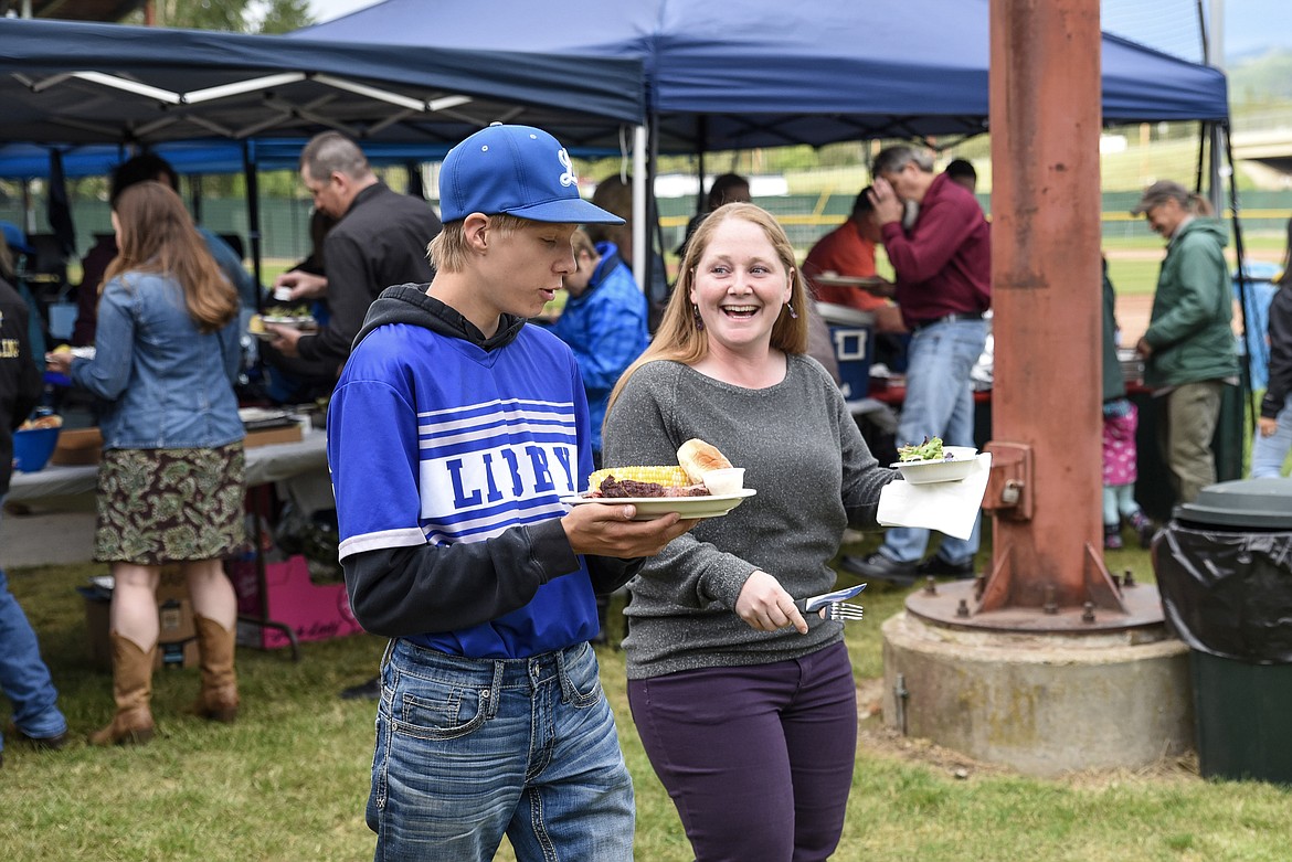 Dawson Rose helps Mandi Foss take her food to her table, during Dinner on the Diamond at Lee Gehring Memorial Field Friday. (Ben Kibbey/The Western News)