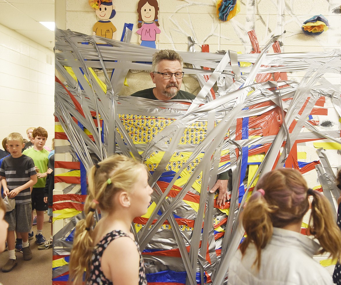 Muldown Assistant Principal John Coyne smiles as students Wednesday morning while he is duct-taped to the wall of the school. Students got to tape two counselors and two administrators to the wall in celebration of their efforts during the Muldown Fun Run. (Heidi Desch/Whitefish Pilot)