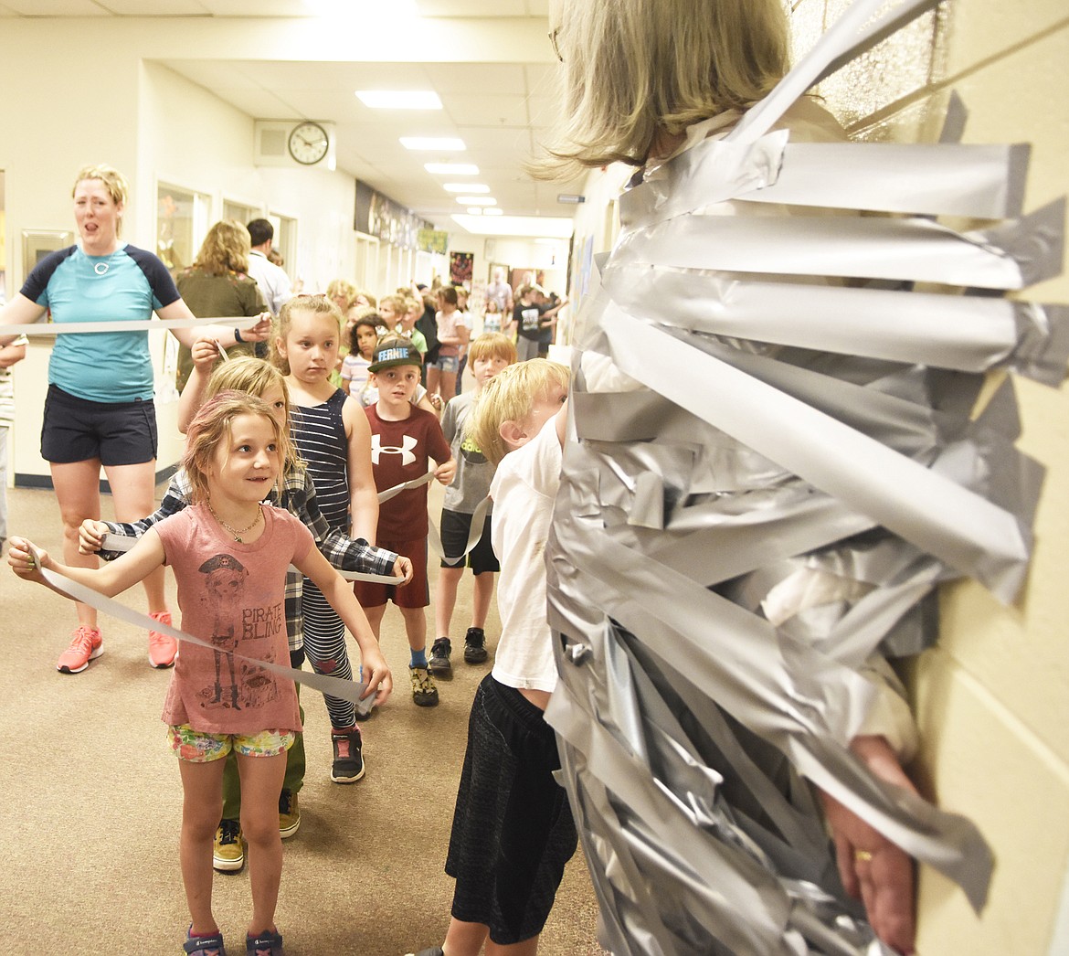 Muldown Elementary student Marley Barge, in pink, smiles while getting ready to put duct tape on Principal Linda Whitright Wednesday morning at the school. (Heidi Desch/Whitefish Pilot)