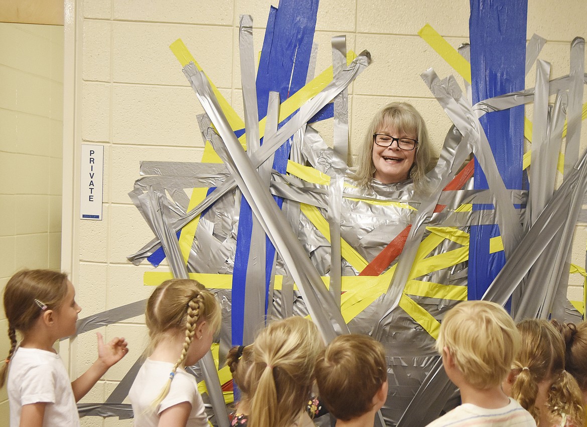 Muldown Principal Linda Whitright laughs with students while being duct-taped to the wall of the school Wednesday morning. Students got to tape two counselors and two administrators to the wall in celebration of their efforts during the Muldown Fun Run. (Heidi Desch/Whitefish Pilot)
