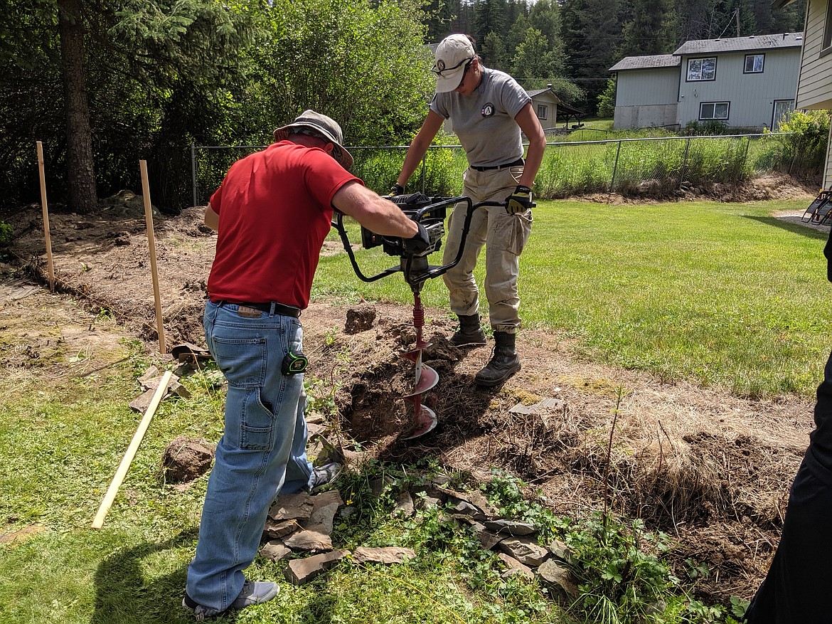 (Left) Mark Cournoyer and Olivia Ramirez use the auger to drill more holes in the groud for new fence posts.