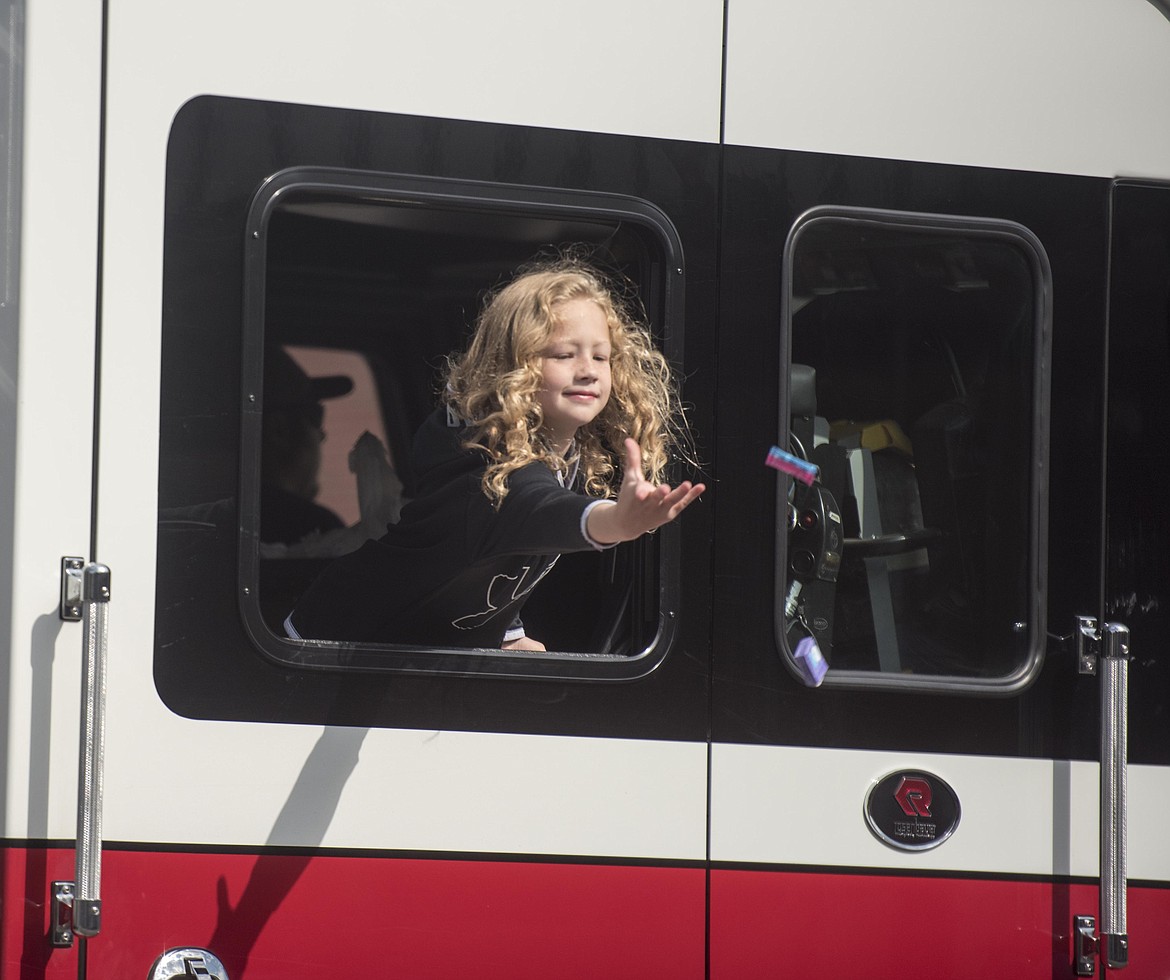 A parade goer tosses candy out of a firetruck for children as they head down Mineral Avenue, Saturday in Libby. (Luke Hollister/The Western News)
