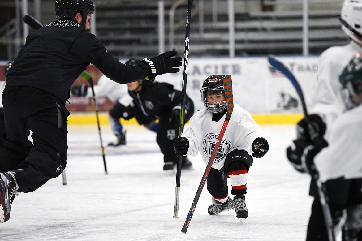 Vinni Ferruzzi, 6, of Missoula, grabs his hockey stick before it could fall to the ice during a drill with Courtney Ports, left, manager of hockey development with the Los Angeles Kings, at the L.A. Kings Summer Camp-Whitefish at Stumptown Ice Den in Whitefish on Thursday. During the drill, campers were instructed to stand their sticks up and, once a whistle was blown, grab their fellow campers' stick before it could fall to the ice. (Casey Kreider/Daily Inter Lake)