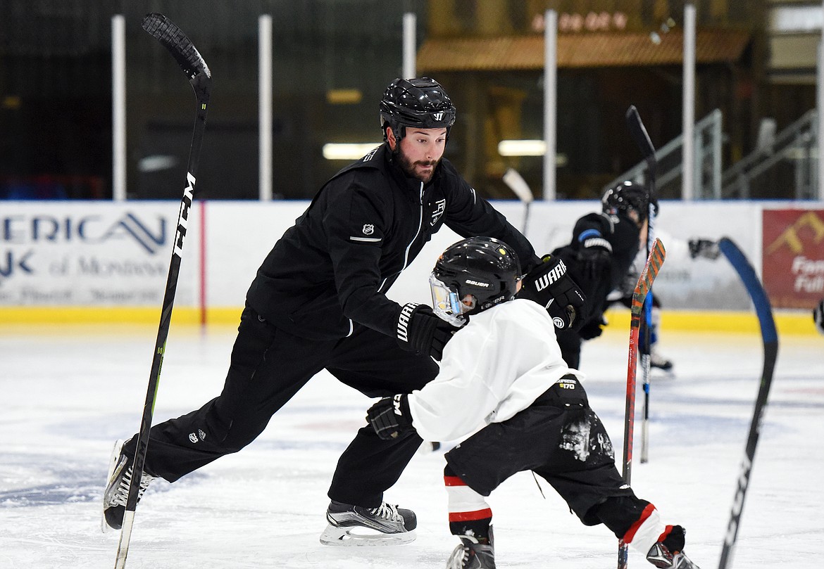 Courtney Ports, manager of hockey development with the Los Angeles Kings, switches sticks during a drill with Vinni Ferruzzi, 6, of Missoula, at the L.A. Kings Summer Camp-Whitefish at Stumptown Ice Den in Whitefish on Thursday. During the drill, campers were instructed to stand their sticks up and, once a whistle was blown, grab their fellow campers' stick before it could fall to the ice. (Casey Kreider/Daily Inter Lake)