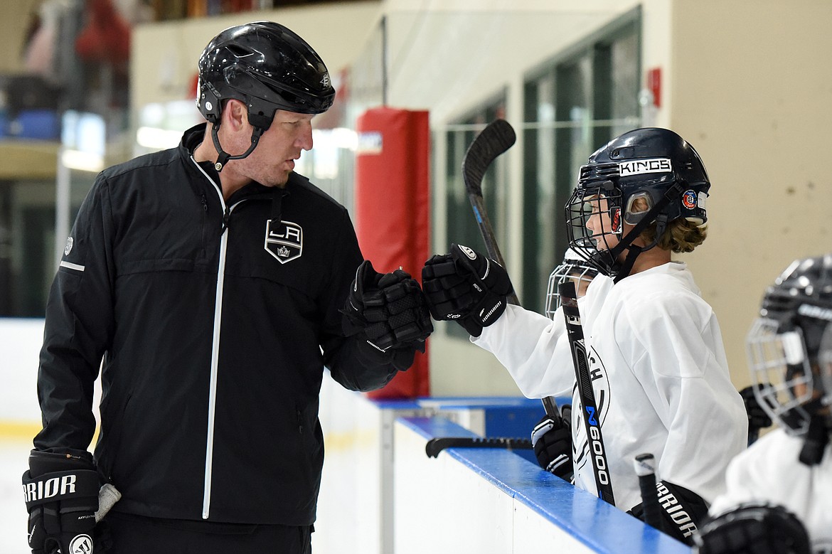 Derek Armstrong, a former Los Angeles King and current director of hockey programming and curriculum with the team, gives a fist bump to Henry Erickson, 9, of Missoula, at the L.A. Kings Summer Camp-Whitefish at Stumptown Ice Den in Whitefish on Thursday. (Casey Kreider/Daily Inter Lake)