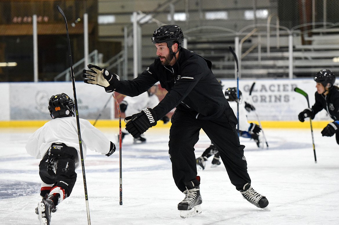 Courtney Ports, manager of hockey development with the Los Angeles Kings, switches sticks during a drill with Vinni Ferruzzi, 6, of Missoula, at the L.A. Kings Summer Camp-Whitefish at Stumptown Ice Den in Whitefish on Thursday. During the drill, campers were instructed to stand their sticks up and, once a whistle was blown, grab their fellow campers' stick before it could fall to the ice. (Casey Kreider/Daily Inter Lake)