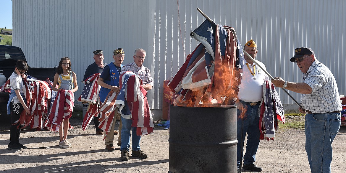 Jerry &#147;Bear&#148; Rote, who served in the Army 1960-62, feeds the flames at the Flag Day retirement ceremony at Polson&#146;s Lakeview Cemetery. In line are John Miller (served in Marine Corps), Bobby Radtke (Air Force Air Rescue), Bud Radtke (Lt. Col. Air Force), Don Lilly (Army Special Forces), and Sydney and Elijah Williams, great-grandchildren of WWII Navy veteran Jim Sivelle, who also attended.