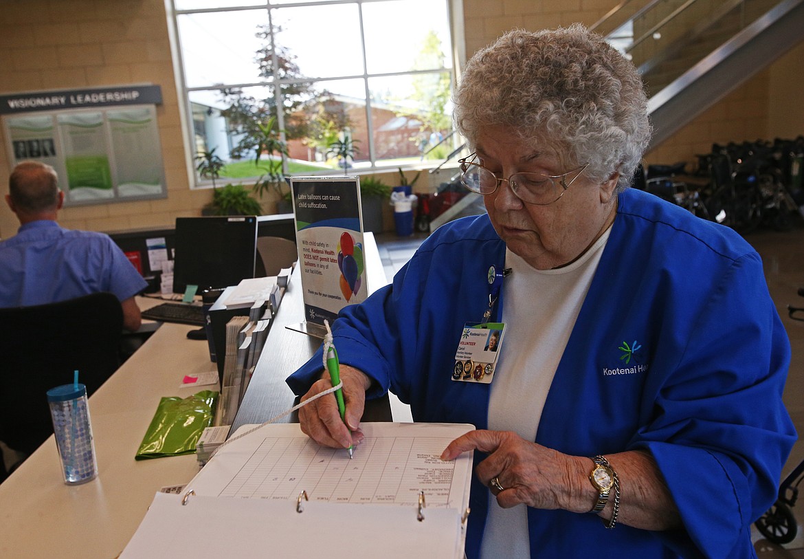 Fourty-five year volunteer Carol Price fills out a volunteer time sheet for Susan Riess at Kootenai Health on Friday. (LOREN BENOIT/Press)