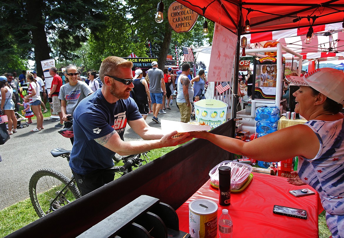 Michele Daniel passes an elephant ear to Kevin Keyworth, of Hayden, at the food court at City Park during Fourth of July. (LOREN BENOIT/Press)