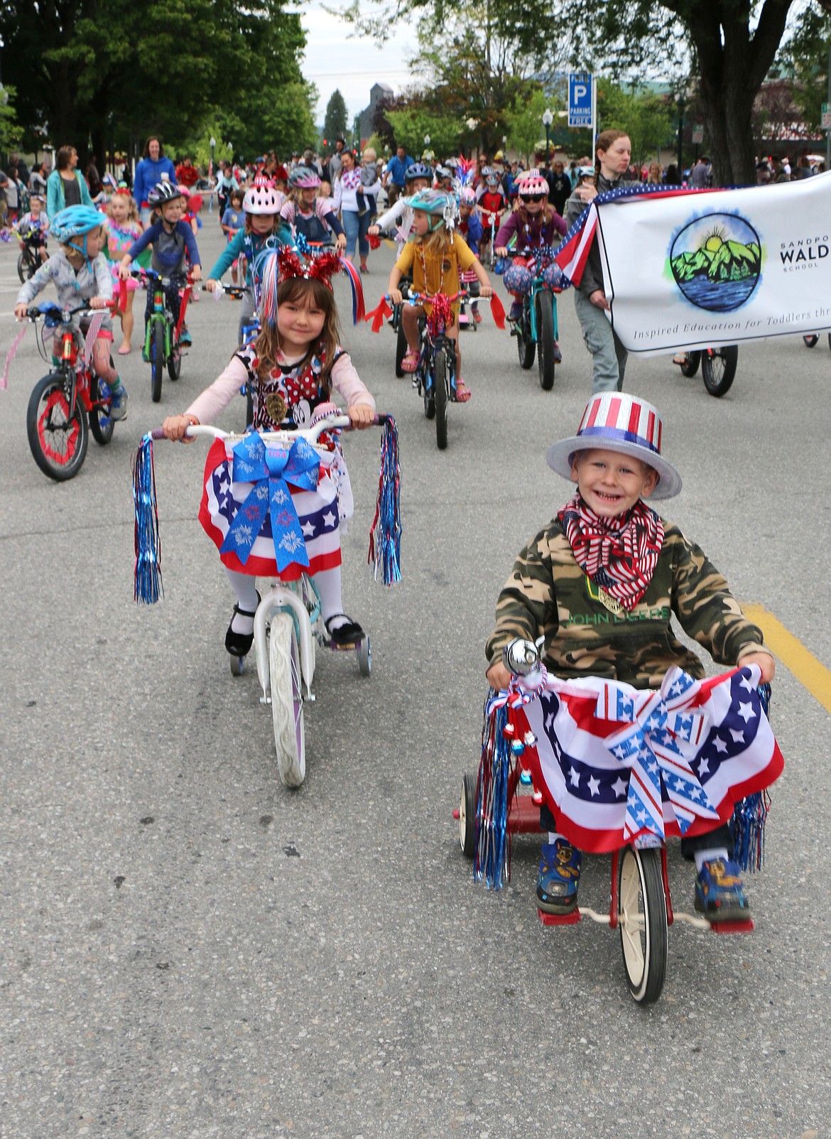 (Photo by CAROLINE LOBSINGER)Young bicyclists smile as they kick off the Sandpoint Lions' Fourth of July Kids Parade on Thursday.