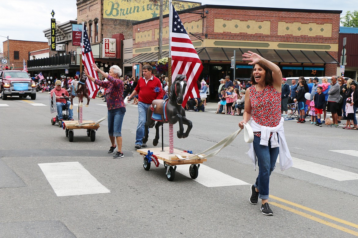 (Photo by CAROLINE LOBSINGER)Carousel of Smiles' Jan Griffitts and Clay and Reno Hutchison wave to the crowd as they take part in the Sandpoint Lions' Fourth of July Grand Parade on Thursday.