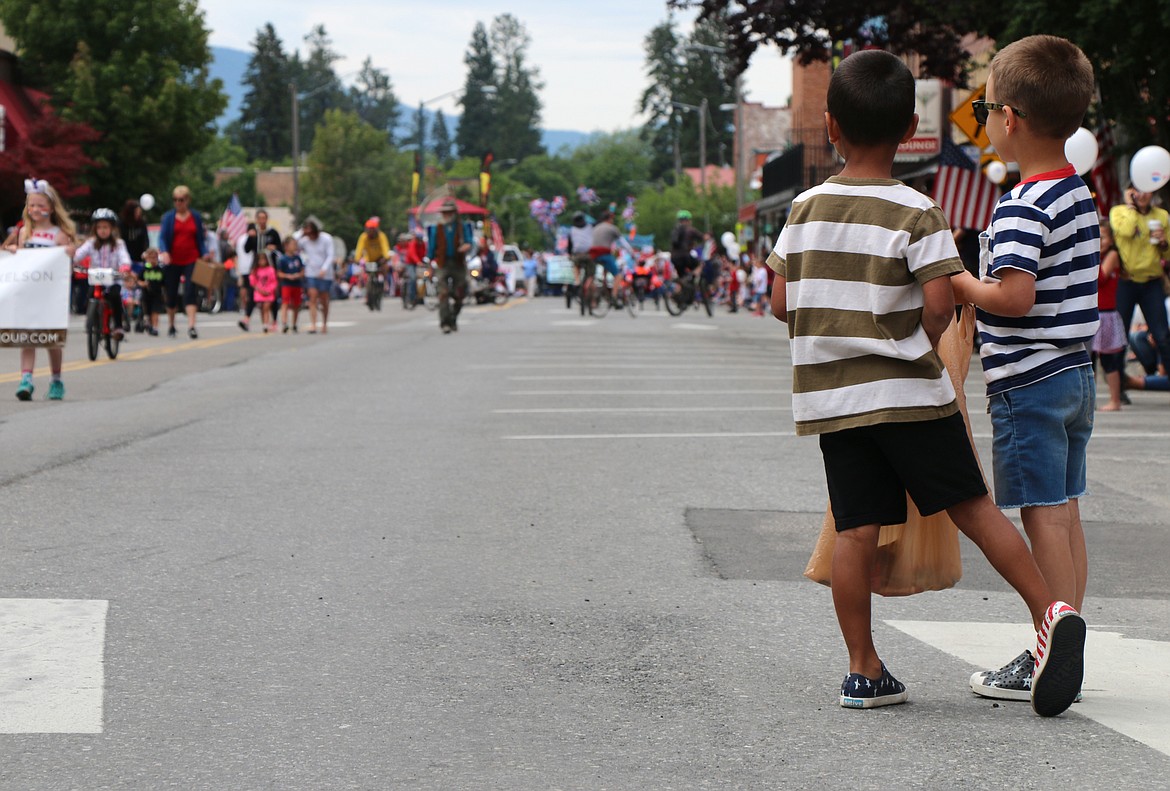 (Photo by CAROLINE LOBSINGER)Young parade watchers hold their bags of candy as they watch the Fourth of July Grand Parade on First Avenue on Thursday.