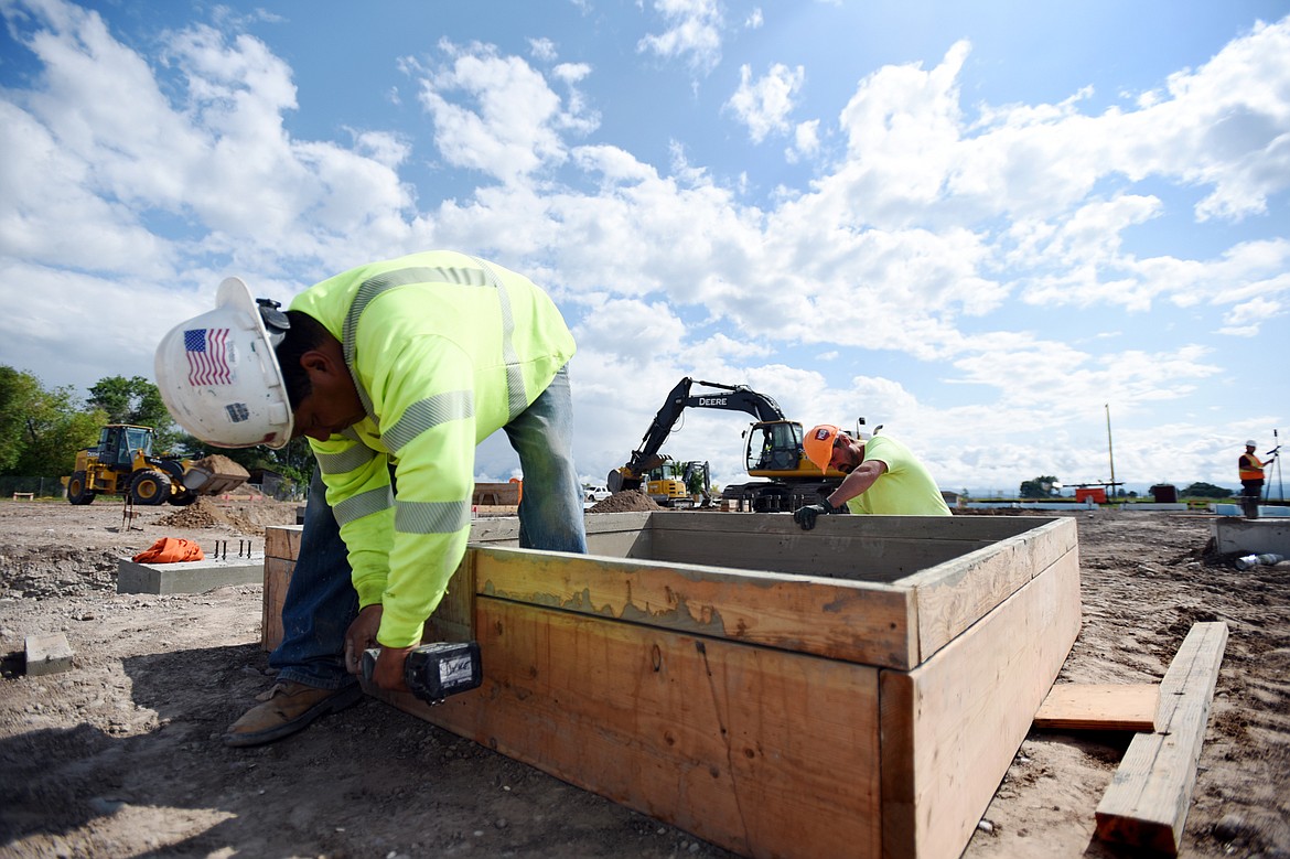 Carl Vaile, left, and Anthony Grady, with Swank Enterprises, work on interior footing pads at Somers Middle School on Wednesday, July 3. (Casey Kreider/Daily Inter Lake)