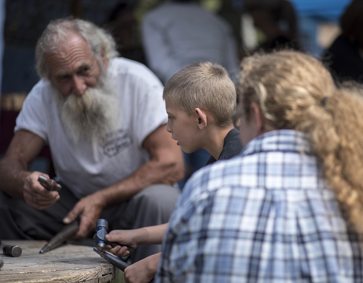 Weezil Samter, left, helps Cole Wilson learn how to hammer out a ring during the Yaak School's 7th Annual Arts and Crafts Fair, Saturday. (Luke Hollister/The Western News)